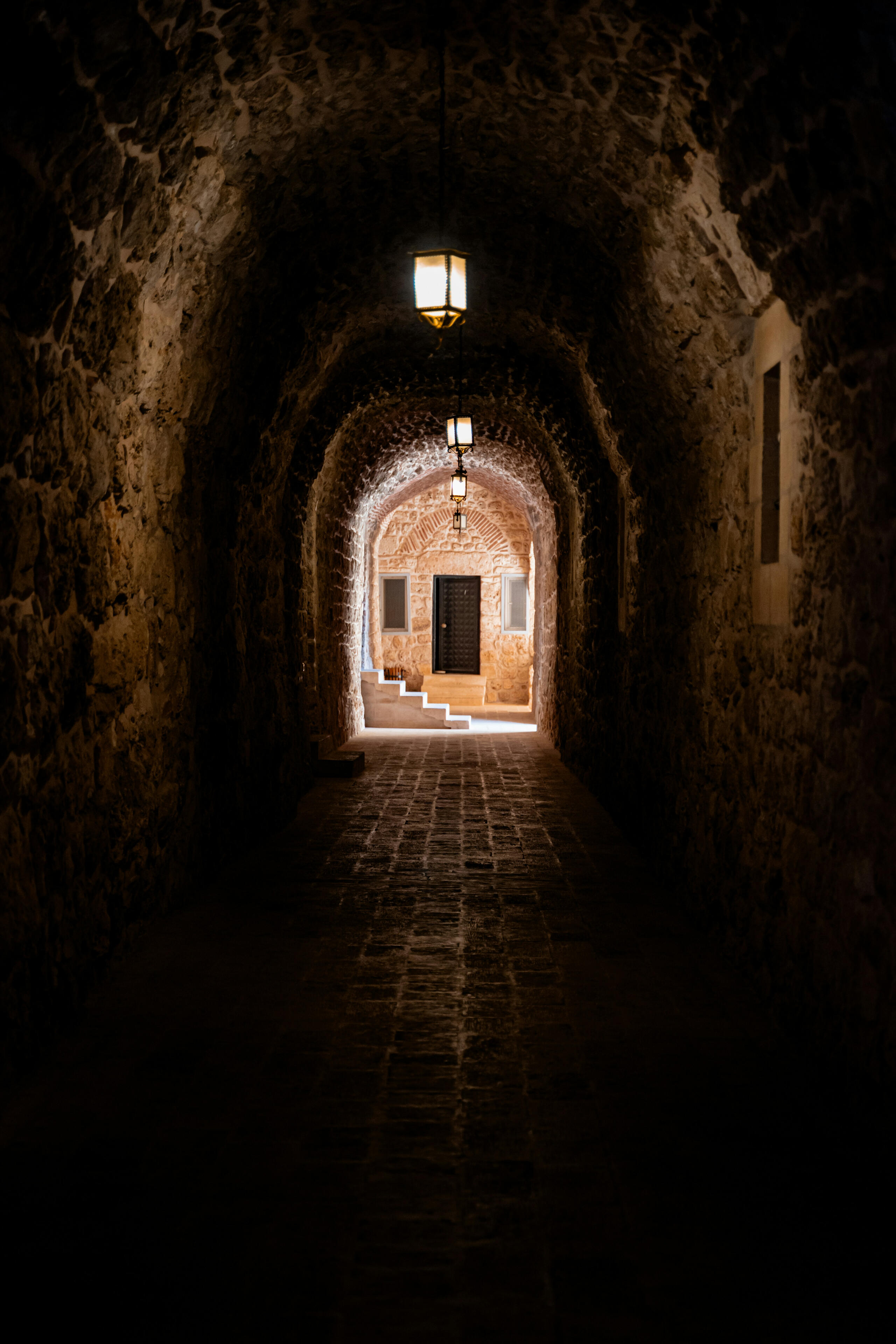 Stone passageway illuminated by hanging lamps